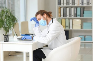 Klinikteki masada oturan yorgun doktor.