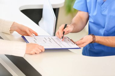 Klinikte hastayla çalışan erkek resepsiyonist, yakın plan.