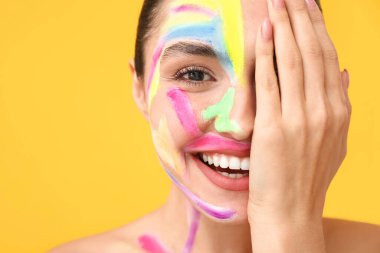 Renkli arka planda yüzü boyalı güzel bir genç kadın.