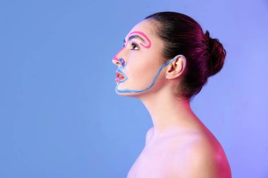 Renkli arka planda yüzü boyalı güzel bir genç kadın.