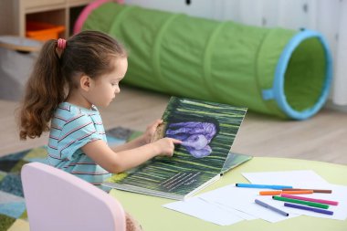 Odada kitap okuyan küçük kız.