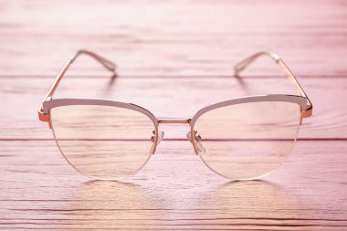 Renkli ahşap arka planda şık gözlükler, yakın plan