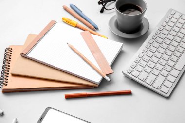 Gri masada farklı ofis aletleri, bir fincan kahve ve cihazlar.