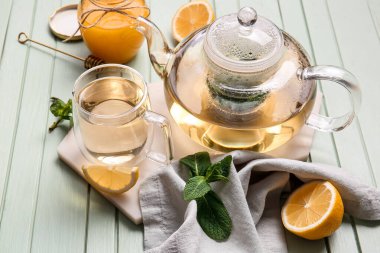 Lezzetli yeşil çay, demlik ve ahşap arka planda malzemelerle dolu bir pano.