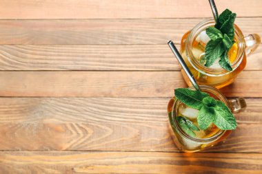 Ahşap arka planda lezzetli buzlu çay kavanozları.