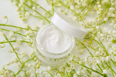 Krema kavanozu ve açık arkaplanda çiçekleri.