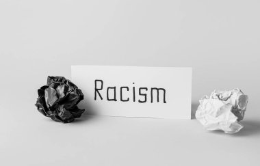 Kağıt parçası kelime RACISM ve beyaz arkaplan üzerine buruşuk kağıtlar
