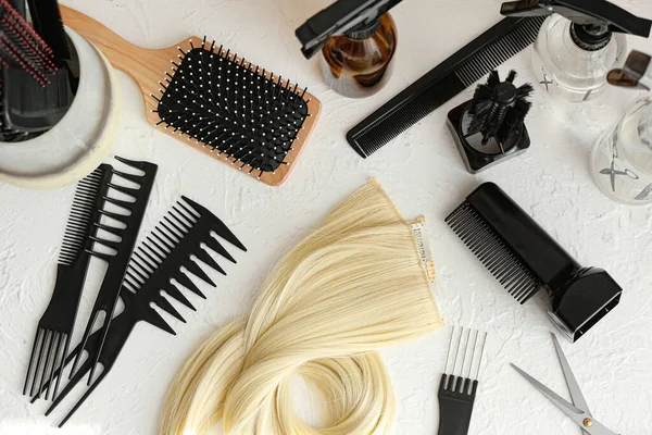 Barber's tools and strand of blonde hair on white background