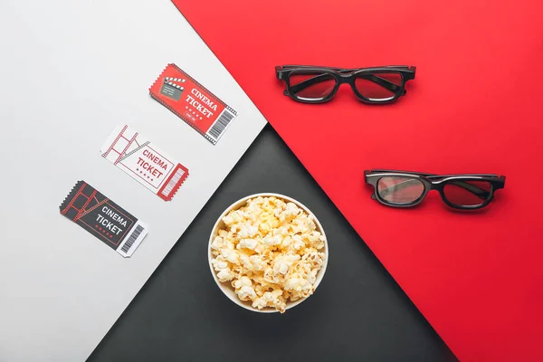 Bowl with popcorn, cinema tickets and 3D glasses on color background