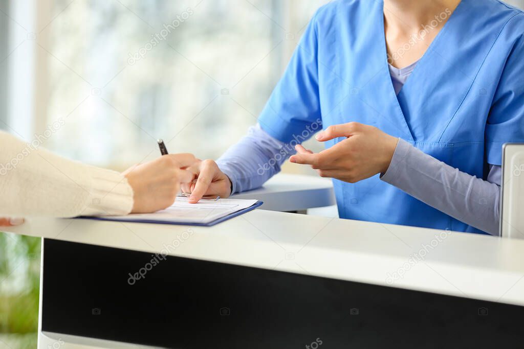 Female receptionist working with patient in clinic