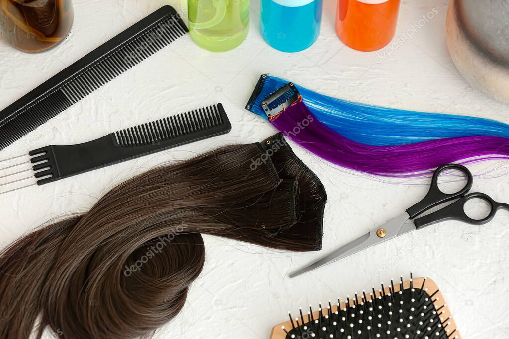 Barber's tools and strands of beautiful hair on white background