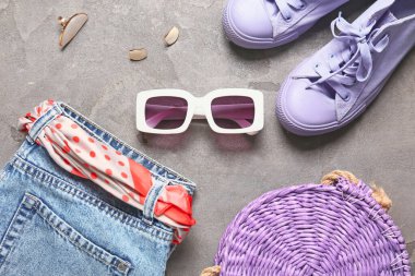 Gri arka planda güneş gözlüklü kadın aksesuarları.