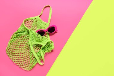 Renkli arka planda şık güneş gözlüğü ve eko çanta