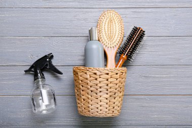 Saç fırçalı sepet, bir şişe kozmetik ürün ve ahşap arka planda sprey.