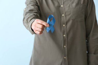 Renkli arka planda mavi kurdeleli adam, yakın plan. Kolon kanseri kavramı