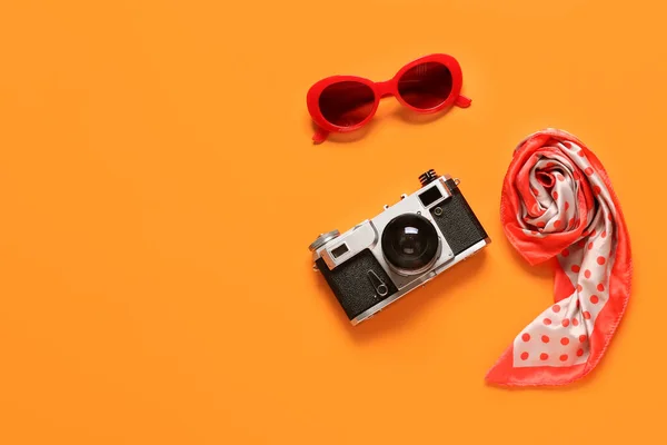 Stylish sunglasses, handkerchief and photo camera on color background