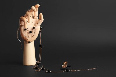 Koyu arkaplanda kadın mücevherleri olan tahta bir el.