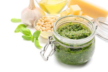 Taze pesto soslu kavanoz ve beyaz arka planda malzemeler.