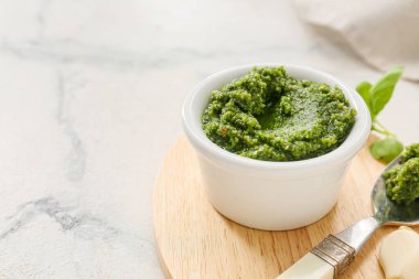 Tahta tahtada taze pesto sosu ve ışık masasında malzemeler var.