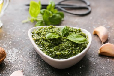 Taze pesto soslu kase ve arkaplanda malzemeler.