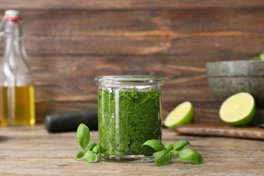 Ahşap arka planda taze pesto soslu kavanoz.