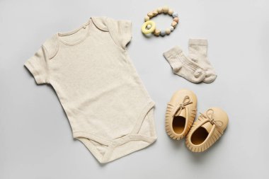 Hafif arka planda bebek kıyafetleri ve oyuncakları.