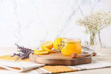 Arkaplanda bal kavanozu, limon ve çiçek olan tahta