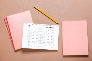 Kağıt takvime, not defterlerine ve renk arkaplanındaki kaleme bak