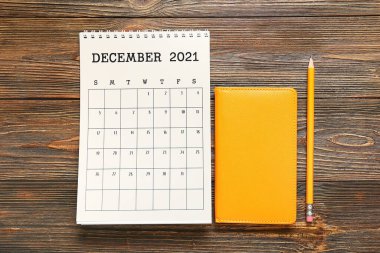 Tahta zemin üzerinde kağıt takvim, defter ve kalem çevirin
