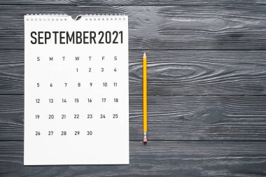 Koyu ahşap zemin üzerinde kağıt takvim ve kalem çevir