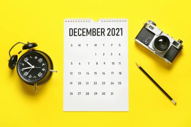 Kağıt takvim, kalem, alarm saati ve renkli arkaplanda fotoğraf makinesi