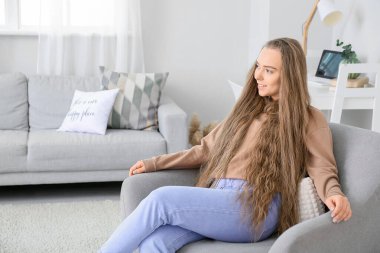 Evdeki koltukta oturan güzel kadın.