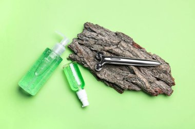 Kozmetik ürünleri şişeleri ile yüz masajı aracı ve renk arka planında ağaç kabuğu