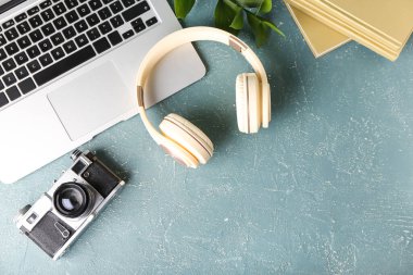Renkli arka planda modern kulaklıklar, dizüstü bilgisayarlar, kitaplar ve fotoğraf makinesi
