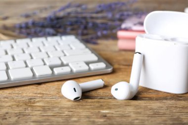 Ahşap arka planda modern kulaklıklar ve bilgisayar klavyesi, yakın plan