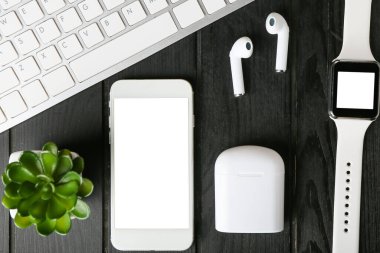 Modern kulaklıklar, bilgisayar klavyesi, cep telefonu ve ahşap arka planda akıllı saat, yakın plan.