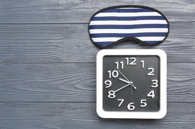 Koyu ahşap arka planda şık saat ve uyku maskesi