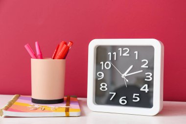 Renk duvarının yanındaki masada şık saat ve kırtasiye malzemesi