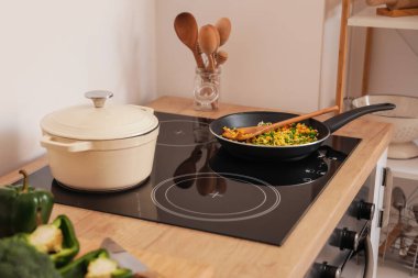 Mutfakta tencere ve tavayla modern elektrikli soba.