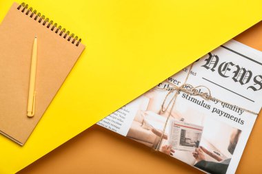 Renk arkaplanı üzerinde not defteri ve kalem olan gazete