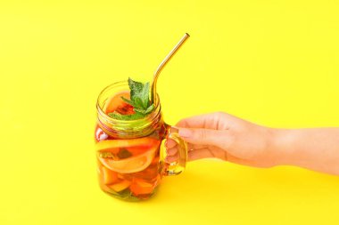 Arka planda bir kavanoz lezzetli buzlu çay ile kadın eli.