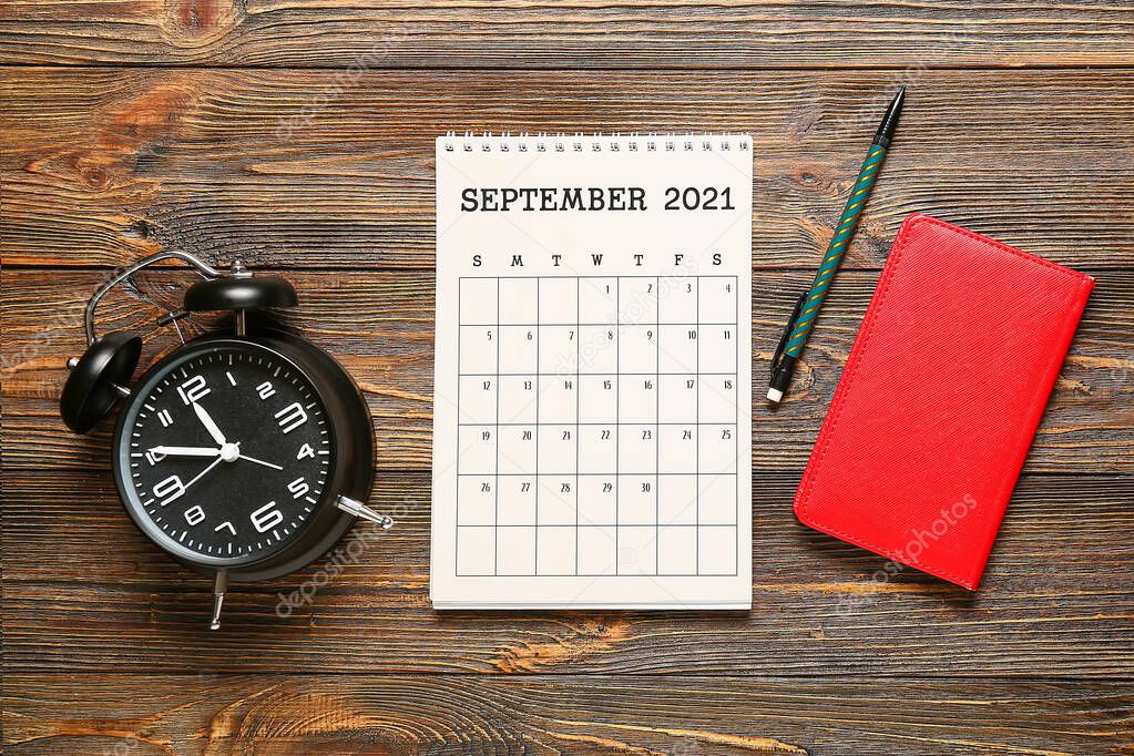 Flip paper calendar, alarm clock, pencil and notebook on wooden background