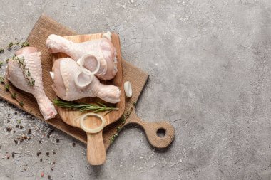 Gri arka planda çiğ tavuk bacaklı tahta
