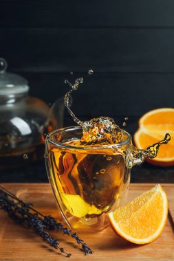 Bir bardak koyu arkaplanlı sıcak narenciye çayı.