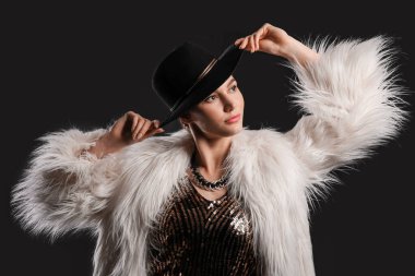 Siyah arka planda şık şapkalı güzel bir kadın.