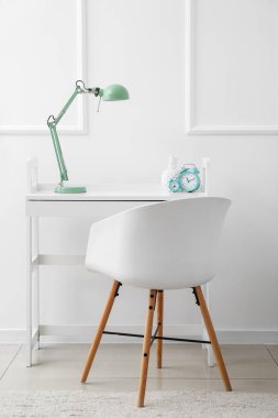 Alarmlı saatleri ve lambasıyla ışık duvarının yanında modern bir işyeri.