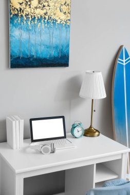 Işık duvarının yanında dizüstü bilgisayarı ve çalar saati olan modern bir işyeri