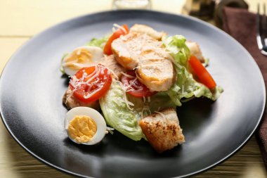 Renkli ahşap arka planda lezzetli Sezar salatası tabağı, yakın plan.