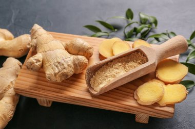 Koyu arkaplanda zencefil tozu ve kökleri olan kepçe