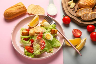 Lezzetli Sezar salatası tabağı ve renkli arka planda malzemeler.